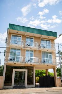 a yellow building with a green roof at Guest House on Rustaveli 176 in Kobuleti