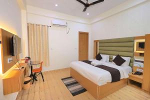 a bedroom with a bed and a desk and a television at Hotel Yuvan Palace - Agra in Tājganj