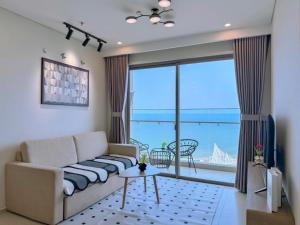 a living room with a couch and a large window at The Song Vung Tau - Infinity Pool & Sea View - Căn Hộ Du Lịch Tháp Tam Thắng - HOUSES BY THE SEA in Vung Tau