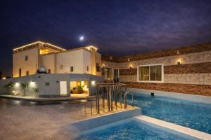 ein Haus mit Swimmingpool bei Nacht in der Unterkunft فيلا وشاليه نسيم لافا in Rayyis