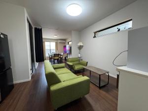 a living room with a green couch and a table at The GameStop in Osaka