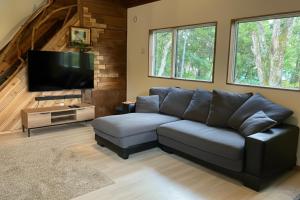 a living room with a couch and a flat screen tv at Chalet Tsugaike in Otari