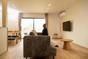 a woman sitting on a couch in a living room at Green Peak 2 in Aso