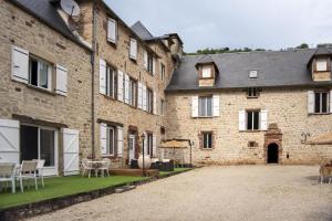 a large brick building with a courtyard with tables and chairs at La Demeure du Comte in Marcillac-Vallon +24 photos
