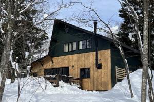 a log cabin in the snow in the woods at Chalet Tsugaike in Otari