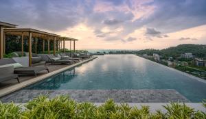a swimming pool with lounge chairs on a building at Mida Grande Resort Phuket Official Account in Surin Beach