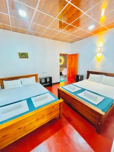 two twin beds in a room with red floors at Chamikara Homestay in Sigiriya