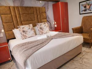 a bedroom with a large bed and a chair at Europrime Hotels Lakefield in Benoni +49 photos