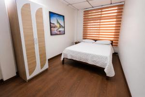 a small bedroom with a bed and a window at Hotel de Alborada - Cerca Del Aeropuerto in Guayaquil