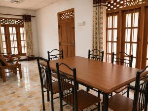 a dining room with a wooden table and chairs at MG Home Sigiriya in Inamaluwa