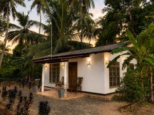 a small white house in front of some palm trees at MG Home Sigiriya in Inamaluwa