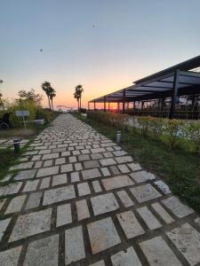 a brick pathway leading to a building with palm trees at Beach House Lleshi in Tale