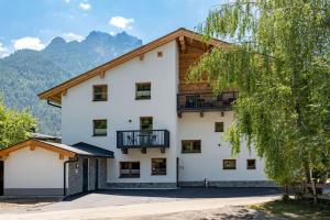a large white building with a wooden roof at Alpenrose Appartements Waidring in Waidring