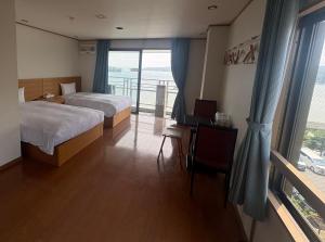 a hotel room with two beds and a large window at ウェルカムイン松島 in Matsushima