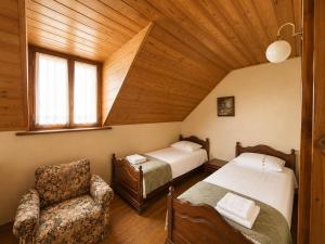a bedroom with two beds and a chair in a room at Milorava's Guest House & Wine Cellar in Telavi