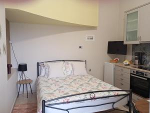 a small bedroom with a bed and a kitchen at Póe home Trikala in Tríkala
