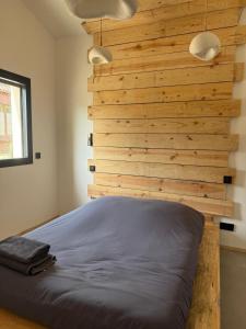 a bedroom with a wooden wall and a bed at La Villa Véga 8 pers in Martillac