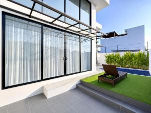 a house with a patio with a chair and grass at Villa Exquisite Central Seminyak by Nagisa Bali in Seminyak