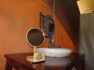 a bathroom sink with a mirror on a table at Sunshine maasai mara safari camp in Sekenani