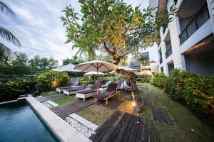 a patio with chairs and an umbrella next to a pool at Padang Padang Inn in Uluwatu
