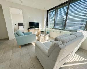 a living room with a couch and a chair and a television at Bondi Beach Escape, Steps to Sand & Cafe in Sydney