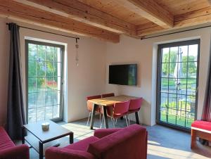 a living room with a table and chairs and windows at Otava apartments - Rezidence Valcha in Sušice