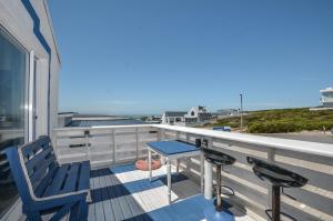 a balcony with a blue table and chairs and the ocean at SONVANGER VILLA YZERFONTEIN in Yzerfontein