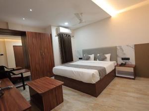 a bedroom with a large bed and a desk at Hotel Anmol One in Indore