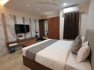 a bedroom with a large bed and a television at Hotel Anmol One in Indore