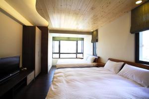 2 Betten in einem Zimmer mit einem TV und einem Bett sidx sidx sidx in der Unterkunft Sung-Ding Guesthouse in Jian