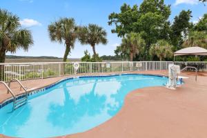 a swimming pool with a fence and palm trees at Sleep Inn Beaufort near MCAS in Beaufort