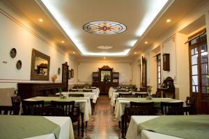 a restaurant with white tables and chairs and a stained glass window at Hotel Aurora in Antigua Guatemala