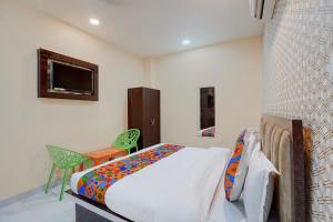 a bedroom with a bed and a chair and a tv at FabHotel Crystal Zee in Kānpur