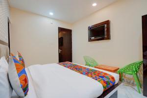 a bedroom with a bed and a tv on the wall at FabHotel Crystal Zee in Kānpur