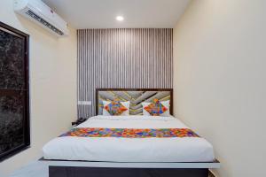 a bedroom with a large white bed with colorful pillows at FabHotel Crystal Zee in Kānpur +26 photos