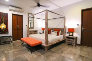 a bedroom with a canopy bed and an orange bench at Villa Yasmin in Seminyak