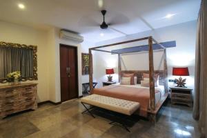 a bedroom with a canopy bed with a bench in it at Villa Yasmin in Seminyak