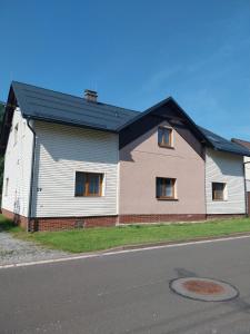 a white house with a black roof on a street at Apartmán U Čápů Mladé Buky 59 in Mladé Buky