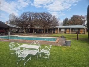 a table and chairs in a yard next to a pool at Chargo River Lodge in Colesberg