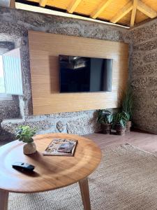 a living room with a table and a tv on a wall at Pedacinho do Céu in Vieira do Minho