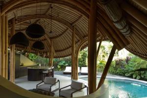 an open pavilion with chairs and a swimming pool at Kaymana in Uluwatu