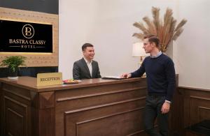 two men standing at a reception desk at Bastra Classy Hotel in Hanoi