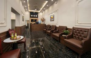 a waiting room with brown leather chairs and a man at Bastra Classy Hotel in Hanoi
