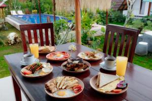 a wooden table with plates of food on it at Maskot Penida Cottage in Nusa Penida