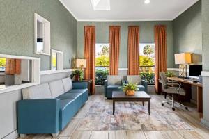 a living room with a blue couch and a desk at Quality Inn near Blue Spring in Orange City
