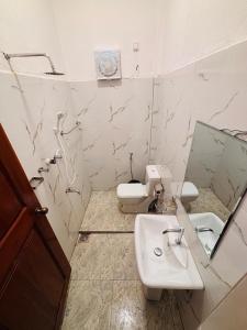 a bathroom with a sink and a toilet and a mirror at Baywatch Arugambay in Arugam Bay