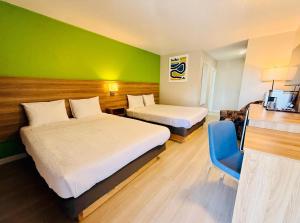 a hotel room with two beds and a green wall at Park Inn by Radisson, Quesnel in Quesnel