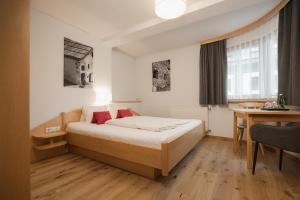 a hotel room with a bed and a desk at Apart Hotel Garni Kofler in Fiss