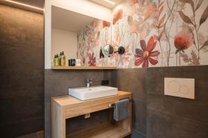 a bathroom with a sink and a flower mural at Apart Hotel Garni Kofler in Fiss +38 photos