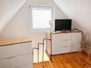 a room with a tv on top of a white cabinet at Zacisze nad Jeziorem- prywatny domek blisko morza in Jezierzany